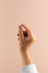 A woman's hand holds a pill with a medicinal supplement . Healthcare, food additives and medicines.