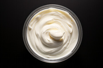 Mayonnaise in a glass bowl on a black background, top view - obrazy, fototapety, plakaty