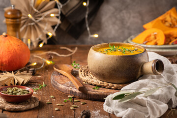 Tasty pumpkin cream soup with organic herbs and pumpkin seeds in vintage ceramic bowl