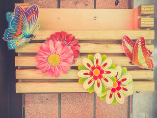 A wooden mailbox decorated with paper flowes and butterflies. Toned image.