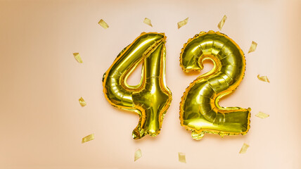 A balloon made of gold foil with the number forty-two. A birthday or anniversary card with the...