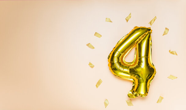 A balloon made of gold foil with the number four. A birthday or anniversary card with the inscription 4. The color is peach fuzz. Anniversary celebration. The banner. copy space
