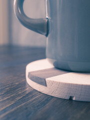 Coffee cup on wooden coaster. Toned image.