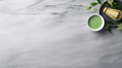 Obraz na płótnie Canvas Elegant flatlay of matcha tea in a white cup, a green macaron, white flowers, and leaves on a marble background, ideal for a serene tea time setting.