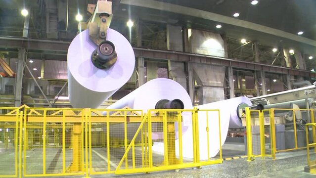 Paper production. Crane operator carries a roll of paper on a crane