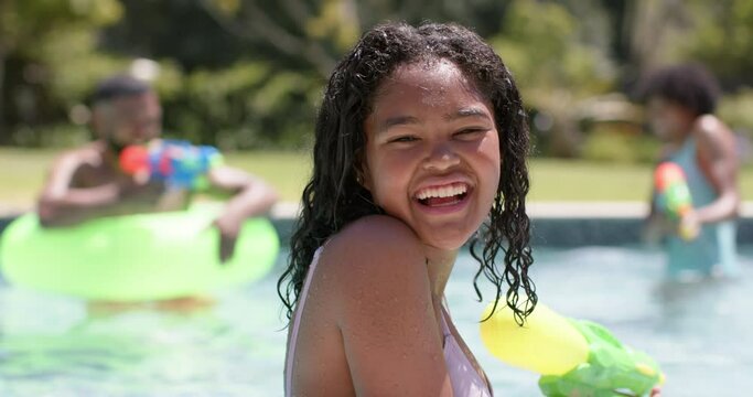 Portrait of happy african american daughter playing with family in sunny pool, slow motion