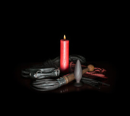 red wax candle with fire and leather whip with rope for tying