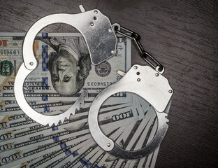 one hundred dollar bills and steel handcuffs close up