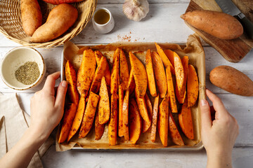 Delicious raw sweet potato wedges, fries on a baking pan.