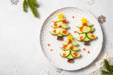 Christmas tree sandwiches with cream cheese and cucumber on a light background, top view