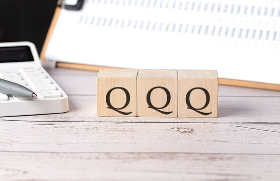QQQ word on a wooden block with clipboard and calcuator