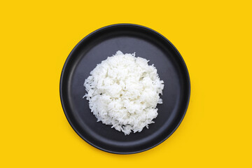 Cooked white rice in black plate on yellow background.