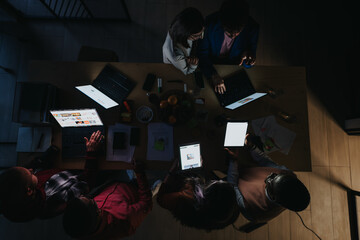 A business team analyzing statistics, discussing a marketing strategy, and working together late at...