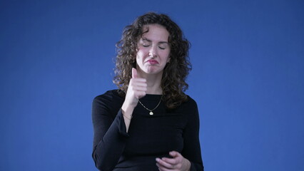 Woman clapping hands congratulating viewer standing on blue background looking at camera signalling...