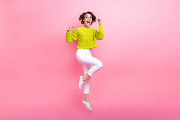 Full length photo of charming lucky girl dressed neon sweater rising fists jumping high isolated...