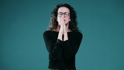 Woman closing her eyes holding her breath while Praying to God for help during difficult times,...