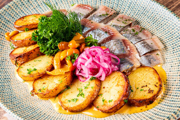 fish herring fillet with potatoes, nushrooms and onions on plate