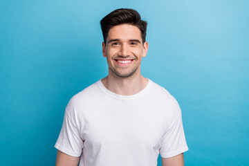 Photo of good mood cheerful guy wear white t-shirt smiling showing teeth isolated blue color...