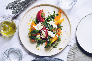Healthy salad with different types of tomatoes, sweet potato, feta cheese and arugula