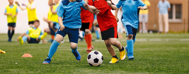 Young boys playing soccer game. Kids having fun in sport. Happy kids compete in football game.. Running soccer players. Competition between players running and kicking football ball. Football school