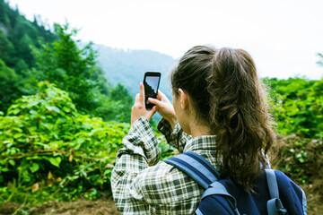 Young female with backpack shooting video of beautiful view using her phone © irocket