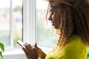 Closeup curly african american woman holding smartphone and typing message