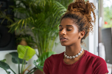 Cropped view of african american woman meditating with closed eyes at home