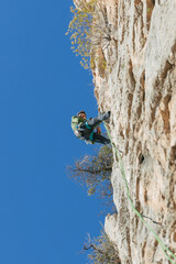 Male mountaineer climbing cliff in daytime