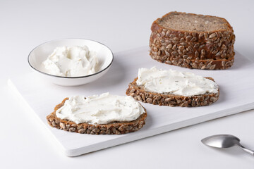 Rye bread with cream cheese on white table. Whole grain rye bread with seeds