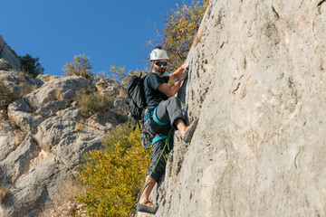Bearded man climbing cliff in daytime