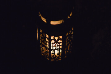 Memory lantern with burning candle in the dark.White Candle Burning in the Dark Night with light glow.Closeup.