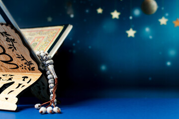 Holy Al Quran and tasbih or rosary beads on blue background.