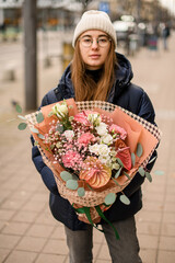 Large bouquet of flowers in the hands of a girl in a white hat
