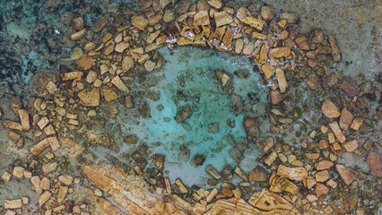 Aerial view from a drone of a natural rock pool in the sea on an Australian beach called Little Bay...