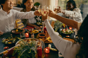 Close up of happy friends is drinking cocktails and clinking glasses during dinner party at home