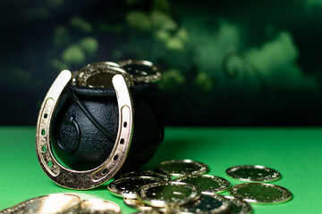 Traditional symbols for St Patrick, Cauldron, gold coins, horseshoe on green background.