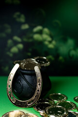 Traditional symbols for St Patrick, Cauldron, gold coins, horseshoe on green background.