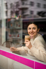 Pretty girl with a glass of coffee in her hands and laptop