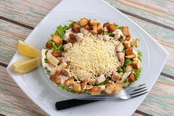 Vegetable salads with lettuce rice ham croutons tomato olives hard-boiled egg arugula carrot lemon cheese on a delivery tray on a white plate