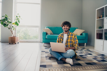 Photo of glad nice successful man hardware expert sitting on floor comfortable apartment working...