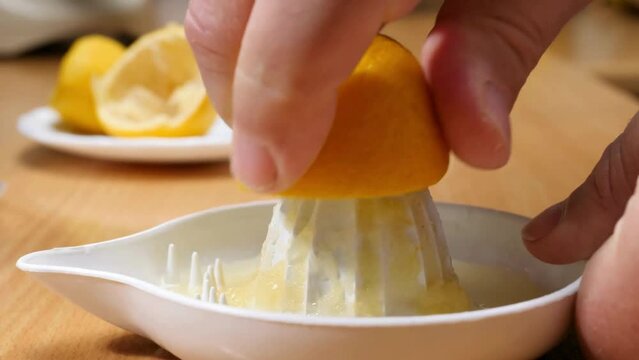 hand squeezes lemon juice on squeezer in close up. Lemon being pressed and juice squeezed out.