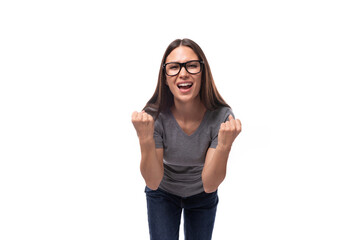 young smiling cute brunette european woman dressed in a gray t-shirt with a mockup on a white background