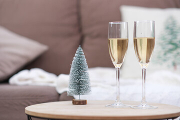 Two glasses of Champagne on caffee table in living room. Christmas home interior. Ceramic christmas tree.