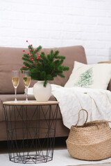Two glasses of Champagne on caffee table in living room. Christmas home interior. Ceramic vase with fir branches.