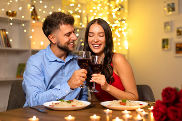 Joyful couple toasting wine glasses at romantic dinner