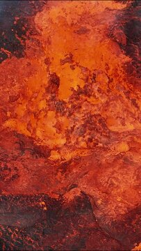 Vertical close up top down view of red hot lava exploding, boiling, and bubbling in the volcano crater, drone shot. Volcanic eruption, natural hazard, and disaster concepts.