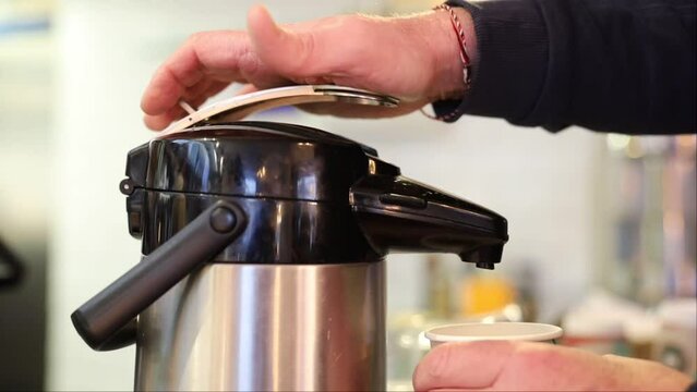 Stockholm, Sweden A man fills a cup of coffee from a thermos in a cafe. 