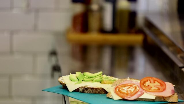 Stockholm, Sweden A male server in a cafe makes a sandwich on the stainless kitchen counter.