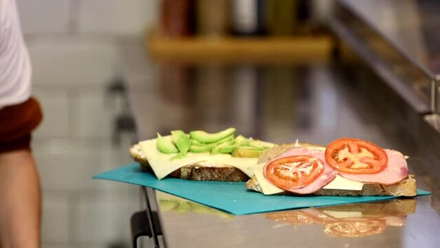 Stockholm, Sweden A male server in a cafe makes a sandwich on the stainless kitchen counter.