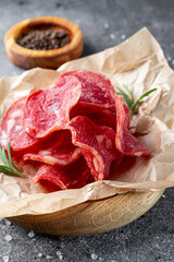 Dried meat on a wooden board and gray background, meat chips vertical photo